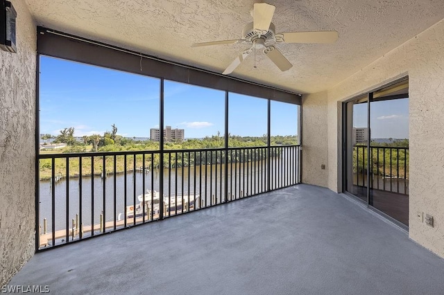 unfurnished sunroom featuring ceiling fan and a water view