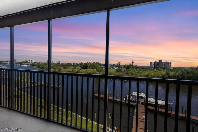 balcony at dusk featuring a view of city and a water view