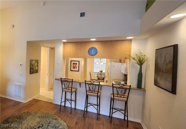 kitchen featuring freestanding refrigerator, wood finished floors, visible vents, and baseboards