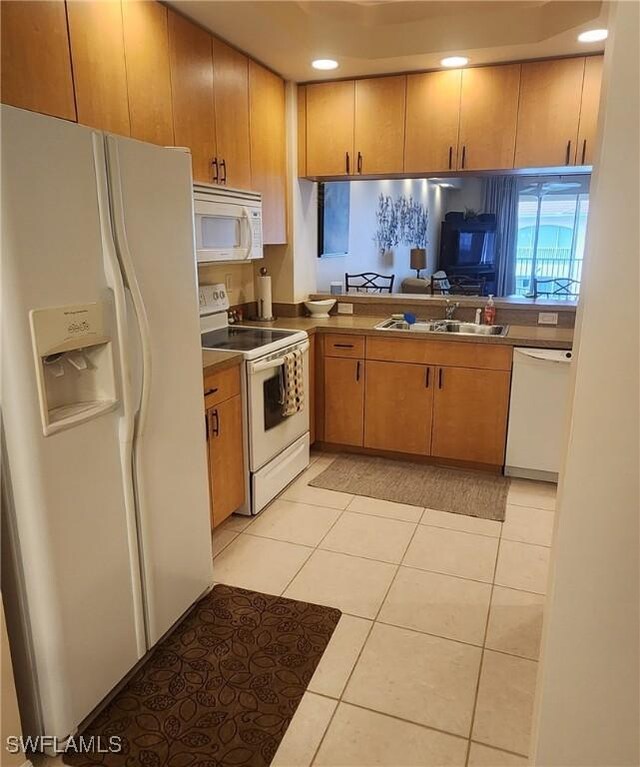 kitchen featuring sink, light tile patterned floors, and white appliances