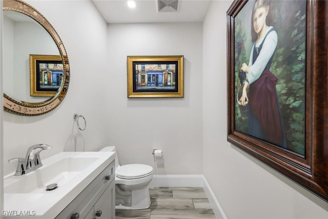 bathroom featuring wood-type flooring, vanity, and toilet