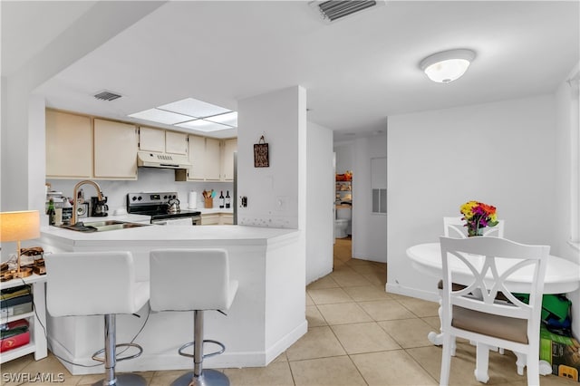 kitchen featuring cream cabinets, light tile patterned flooring, sink, stainless steel electric range oven, and kitchen peninsula