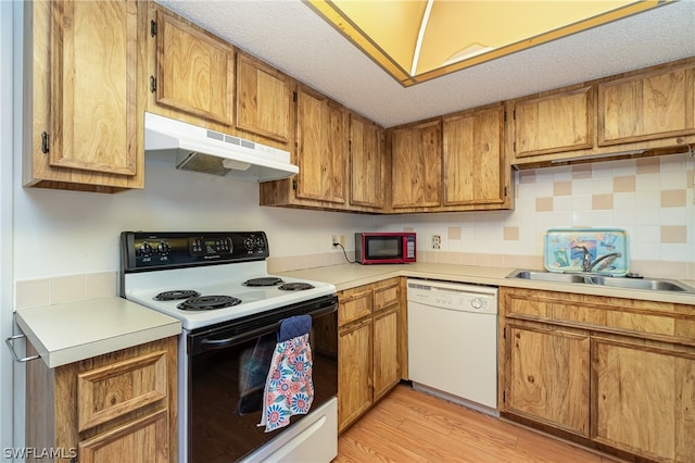 kitchen with light hardwood / wood-style flooring, tasteful backsplash, white appliances, a textured ceiling, and sink