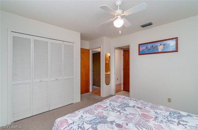 carpeted bedroom with a textured ceiling, a closet, and ceiling fan