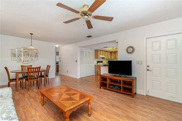 living room with a textured ceiling, light hardwood / wood-style flooring, and ceiling fan