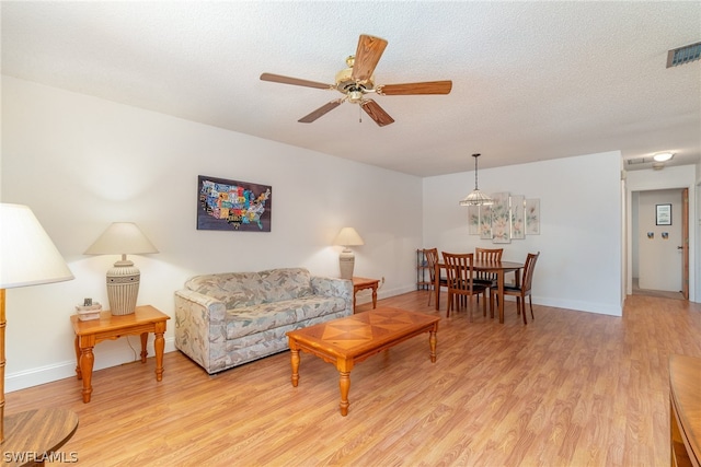 living room with light hardwood / wood-style floors, a textured ceiling, and ceiling fan