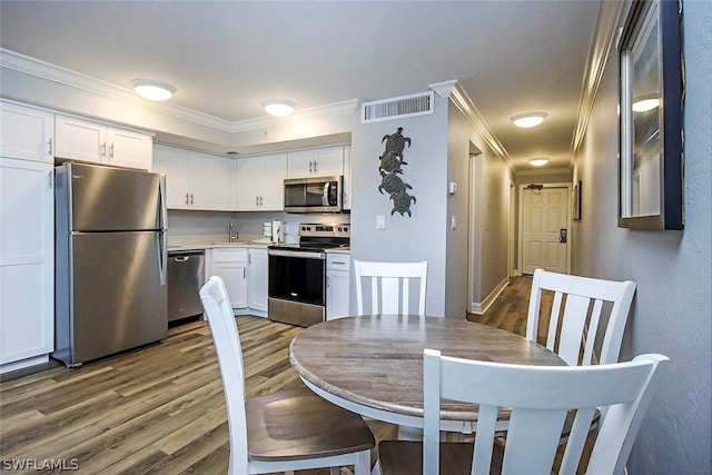 dining space featuring wood-type flooring, sink, and ornamental molding