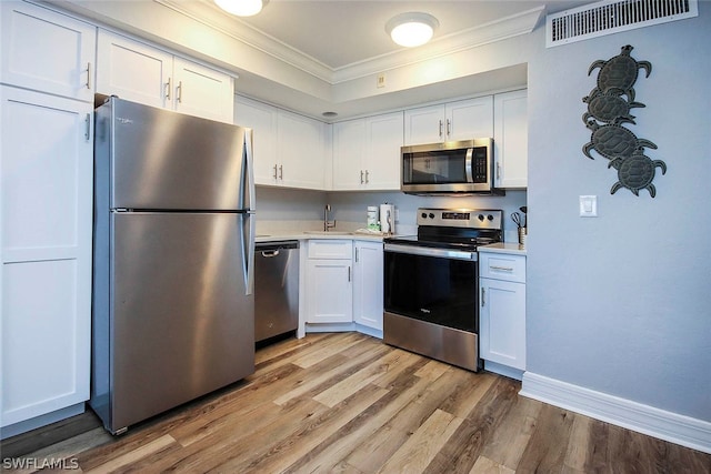 kitchen featuring sink, appliances with stainless steel finishes, white cabinets, and light wood-type flooring