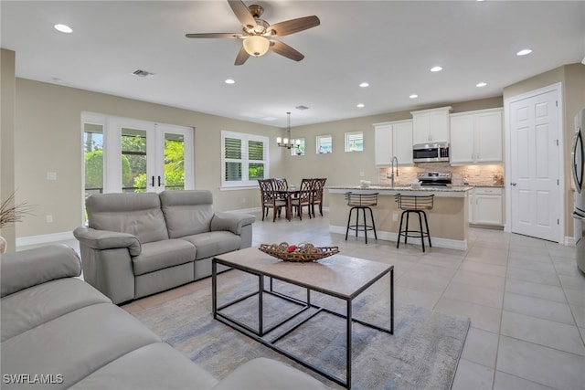 living room with light tile patterned flooring, ceiling fan with notable chandelier, sink, and a wealth of natural light