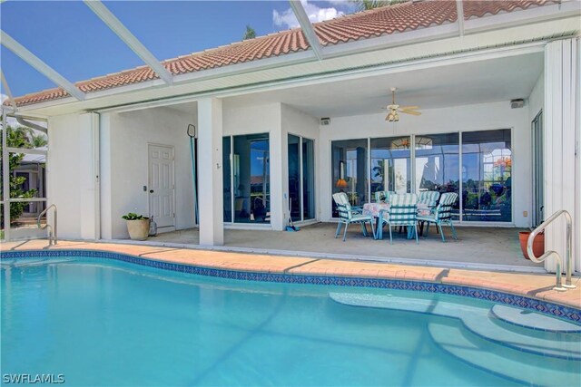 view of swimming pool with a patio area, ceiling fan, and glass enclosure