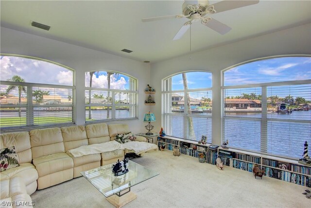 carpeted living room with a water view and ceiling fan