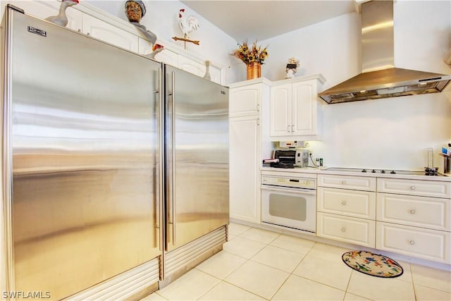 kitchen with stainless steel built in refrigerator, ventilation hood, white cabinets, black electric cooktop, and oven