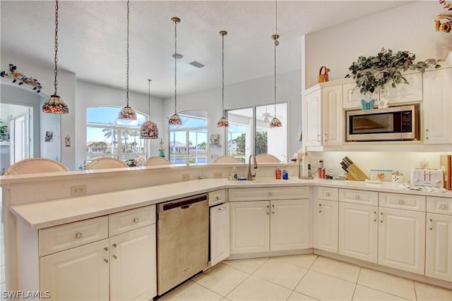 kitchen featuring sink, light tile patterned floors, appliances with stainless steel finishes, pendant lighting, and white cabinets