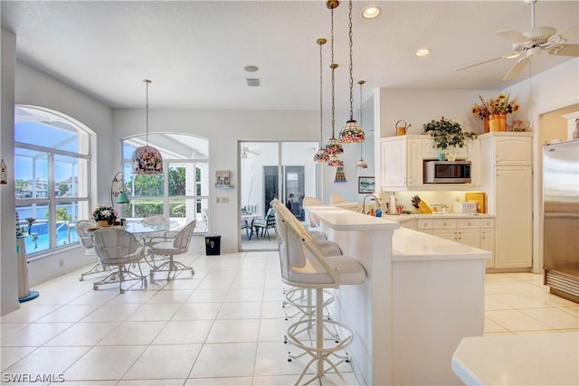 kitchen featuring pendant lighting, appliances with stainless steel finishes, a center island with sink, and light tile patterned floors