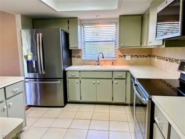 kitchen with decorative backsplash, stainless steel appliances, and green cabinets