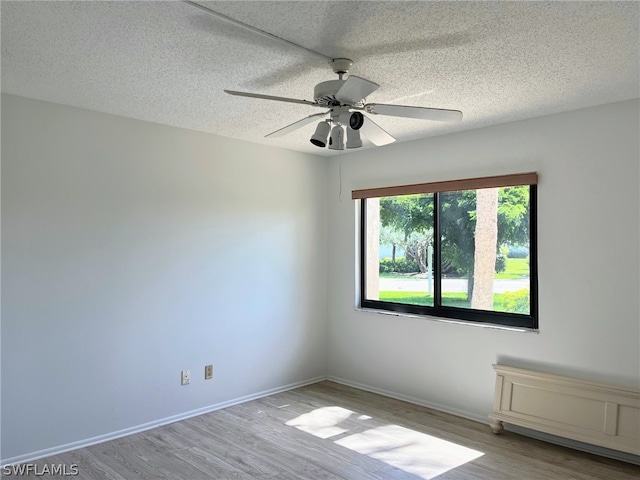 unfurnished room featuring a textured ceiling, ceiling fan, and light wood-type flooring