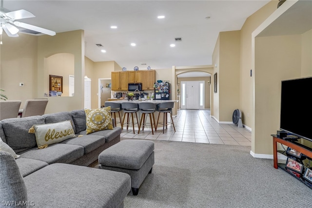 living room featuring ceiling fan, light carpet, and sink