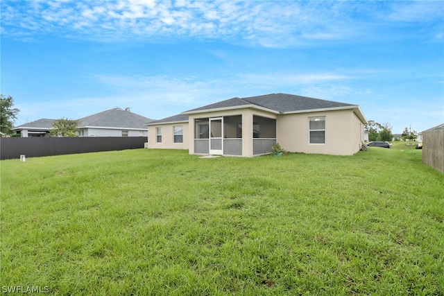 rear view of property featuring a sunroom and a yard