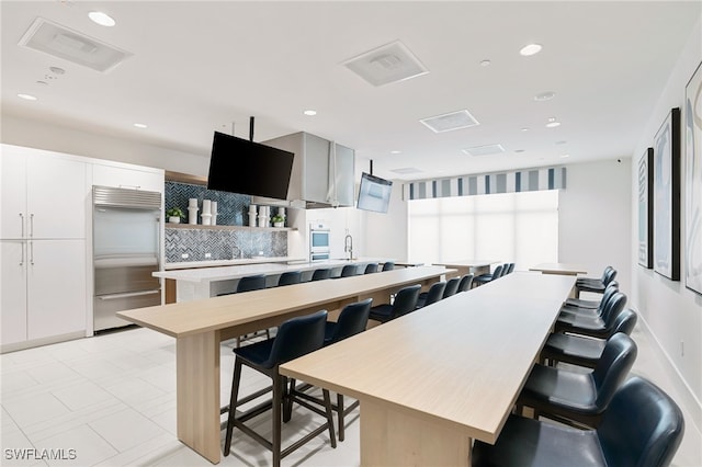 kitchen featuring decorative backsplash, a kitchen island, a kitchen breakfast bar, and built in refrigerator