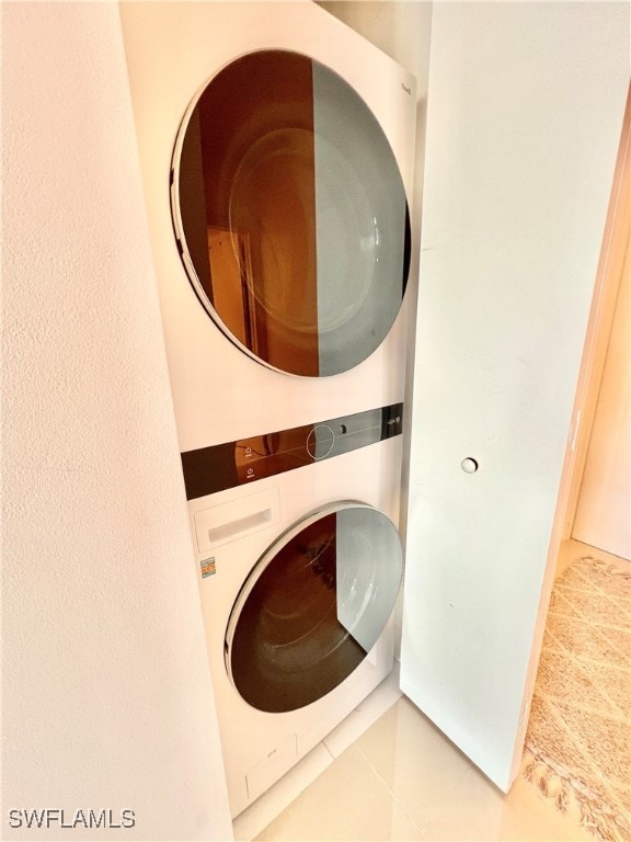 laundry area with tile patterned floors and stacked washer and clothes dryer