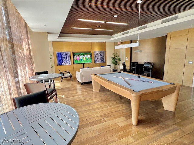 recreation room featuring light wood-type flooring, a raised ceiling, and pool table