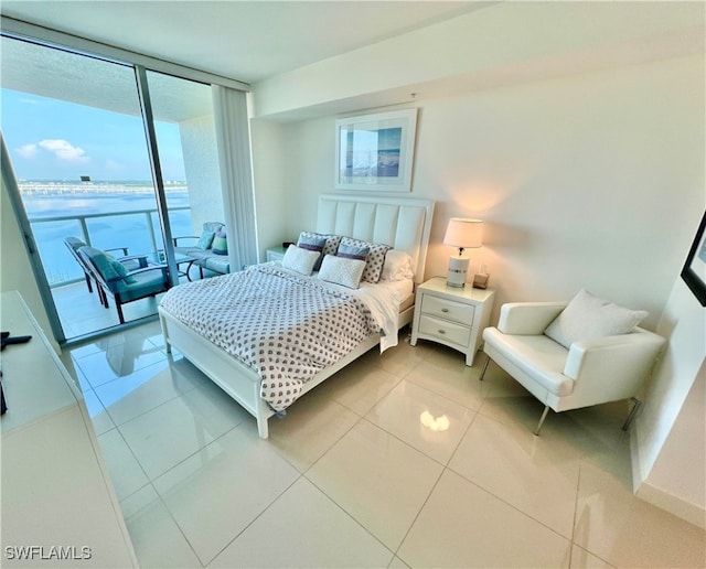 bedroom featuring a water view, expansive windows, light tile patterned flooring, and access to outside