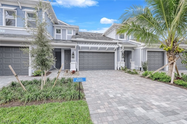 view of front of home with decorative driveway, an attached garage, and stucco siding