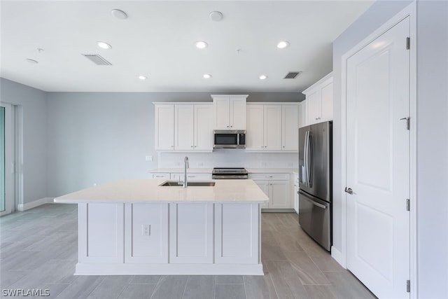 kitchen featuring visible vents, white cabinets, stainless steel appliances, and a sink