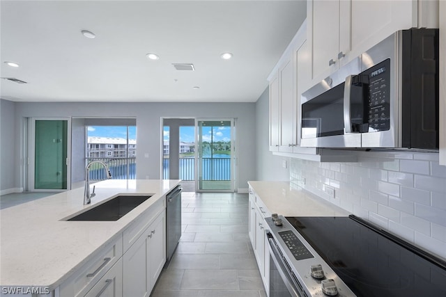 kitchen with appliances with stainless steel finishes, visible vents, a sink, and tasteful backsplash