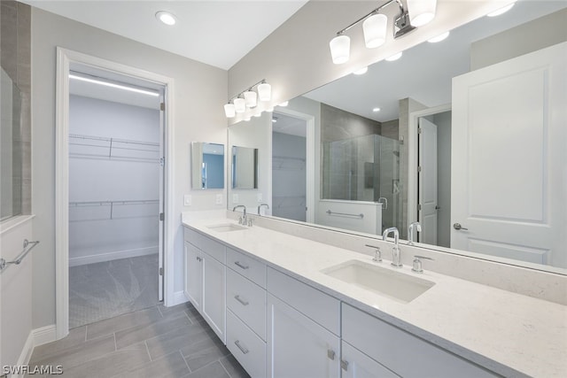 full bathroom with a sink, a walk in closet, a stall shower, and double vanity