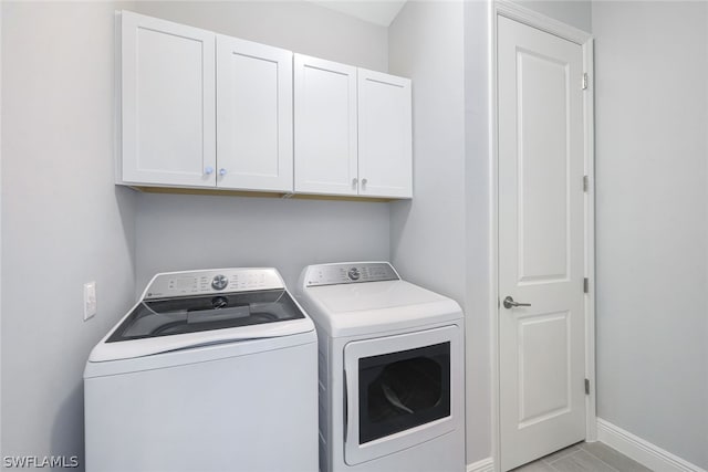 laundry area with cabinet space, independent washer and dryer, and baseboards