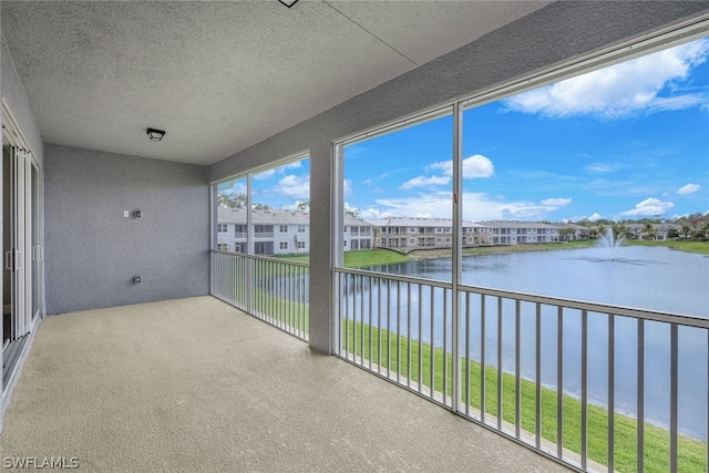 unfurnished sunroom featuring a water view and a residential view