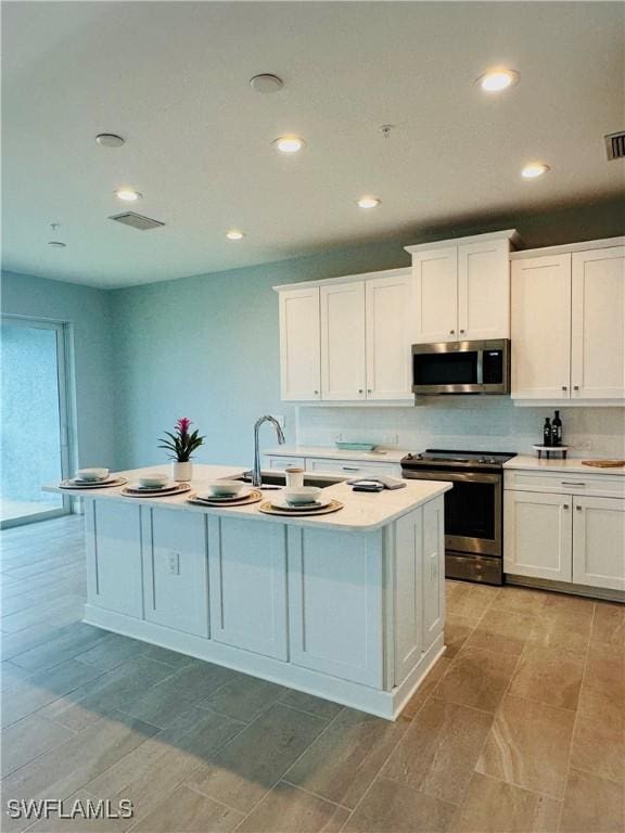 kitchen featuring recessed lighting, a sink, stainless steel appliances, light countertops, and white cabinets