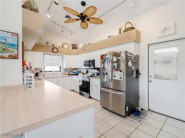 kitchen featuring ceiling fan, stainless steel appliances, white cabinets, vaulted ceiling, and light tile patterned flooring