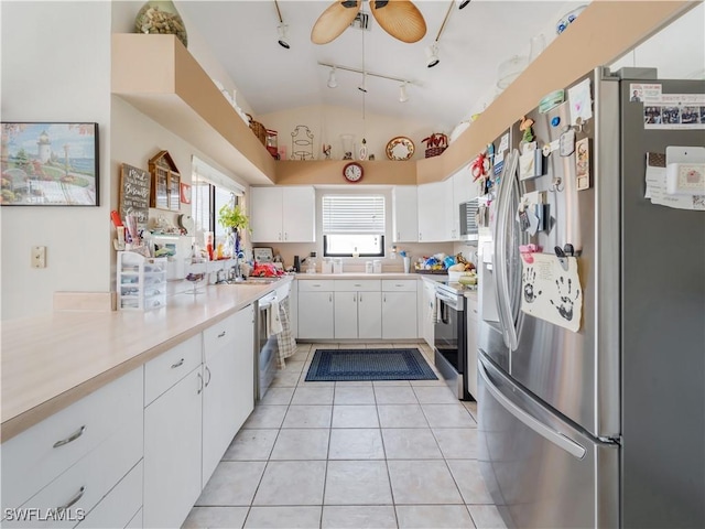 kitchen with stainless steel appliances, ceiling fan, light tile patterned floors, white cabinets, and lofted ceiling