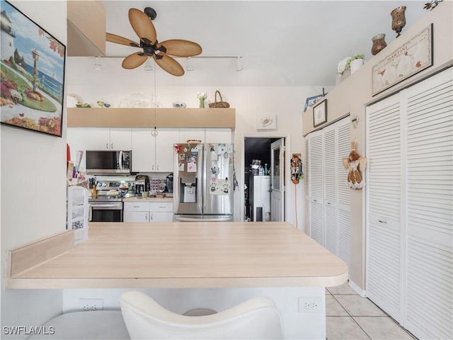 kitchen with white cabinetry, ceiling fan, light tile patterned flooring, kitchen peninsula, and stainless steel appliances