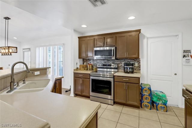 kitchen featuring decorative light fixtures, sink, appliances with stainless steel finishes, light tile patterned floors, and backsplash