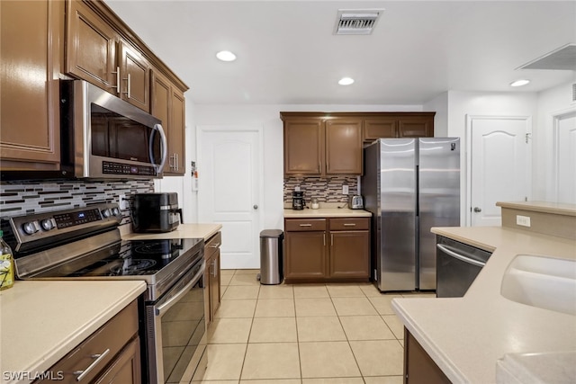 kitchen with decorative backsplash, appliances with stainless steel finishes, and light tile patterned floors