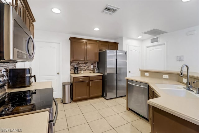 kitchen with sink, decorative backsplash, stainless steel appliances, and light tile patterned floors