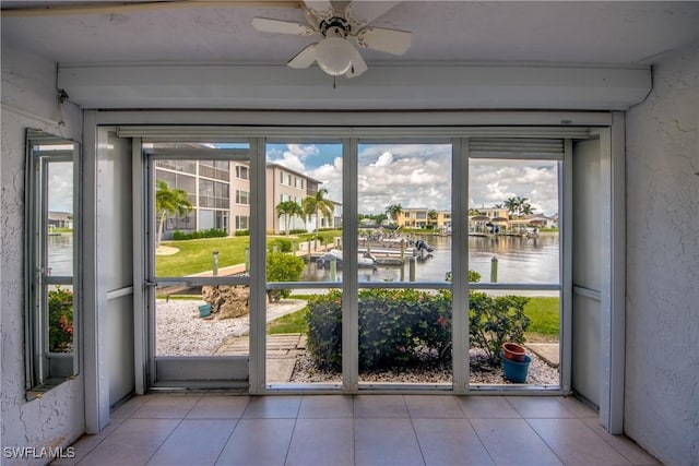 doorway to outside with a water view, a healthy amount of sunlight, light tile patterned floors, and ceiling fan