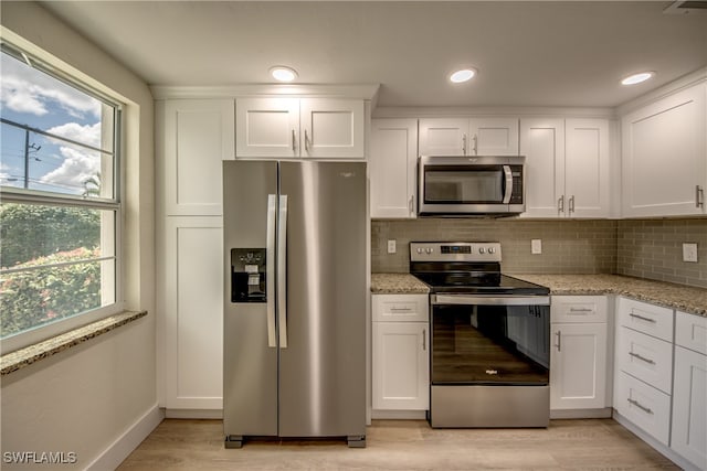 kitchen featuring tasteful backsplash, a wealth of natural light, stainless steel appliances, and light hardwood / wood-style floors