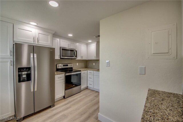 kitchen featuring stainless steel appliances, decorative backsplash, white cabinetry, light hardwood / wood-style flooring, and light stone counters