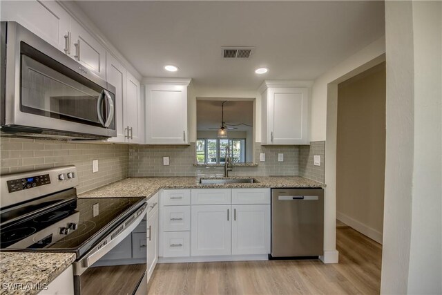 kitchen featuring tasteful backsplash, light wood-type flooring, white cabinets, and stainless steel appliances