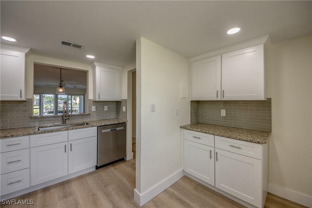 kitchen with sink, white cabinetry, light stone counters, light hardwood / wood-style flooring, and stainless steel dishwasher