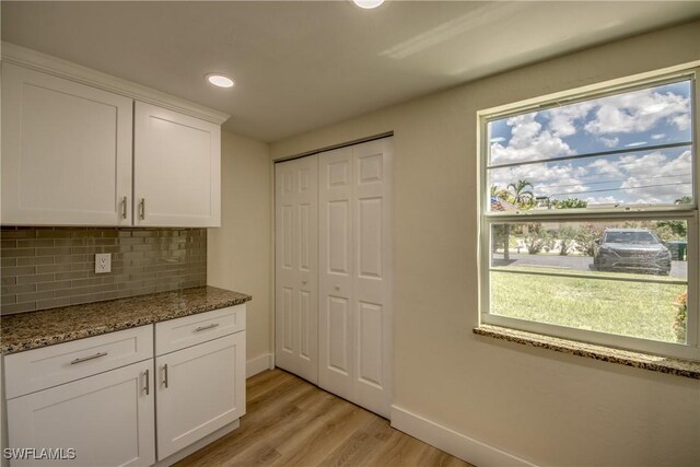 kitchen featuring decorative backsplash, white cabinetry, light hardwood / wood-style floors, and a healthy amount of sunlight