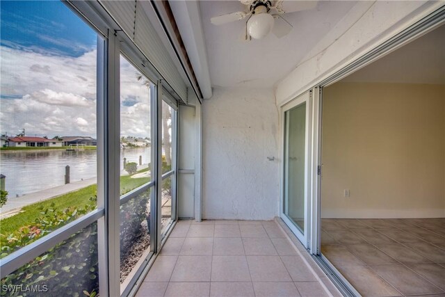 unfurnished sunroom featuring ceiling fan and a water view