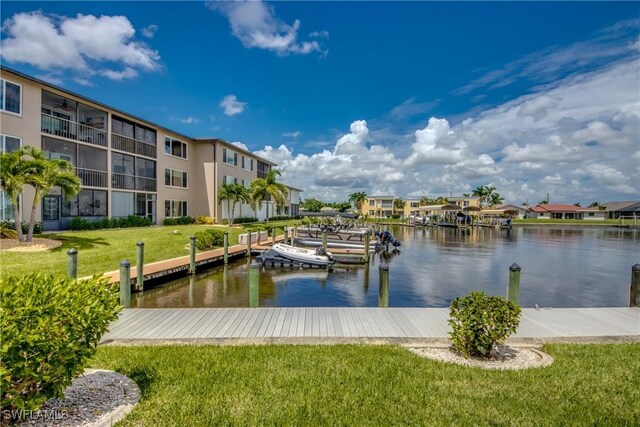 view of dock with a lawn and a water view