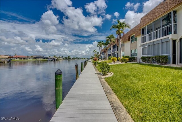 view of dock with a water view and a lawn