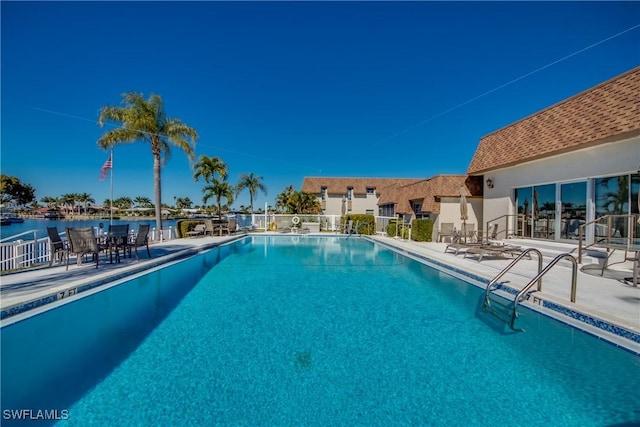 view of pool featuring a patio and a water view