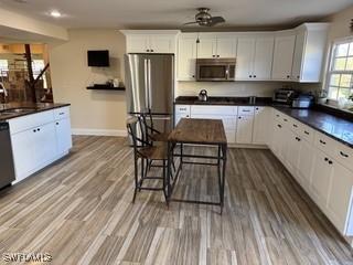 15700 Bahama Way, Bokeelia, FL 33922 - kitchen featuring appliances with stainless steel finishes, baseboards, dark countertops, white cabinets, and ceiling fan